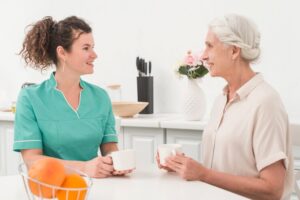 beautiful-young-female-nurse-having-coffee-with-senior-woman_23-2147861589